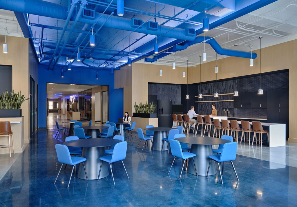 Cafeteria with full kitchen blue flooring, seating, and a blue painted industrial style ceiling