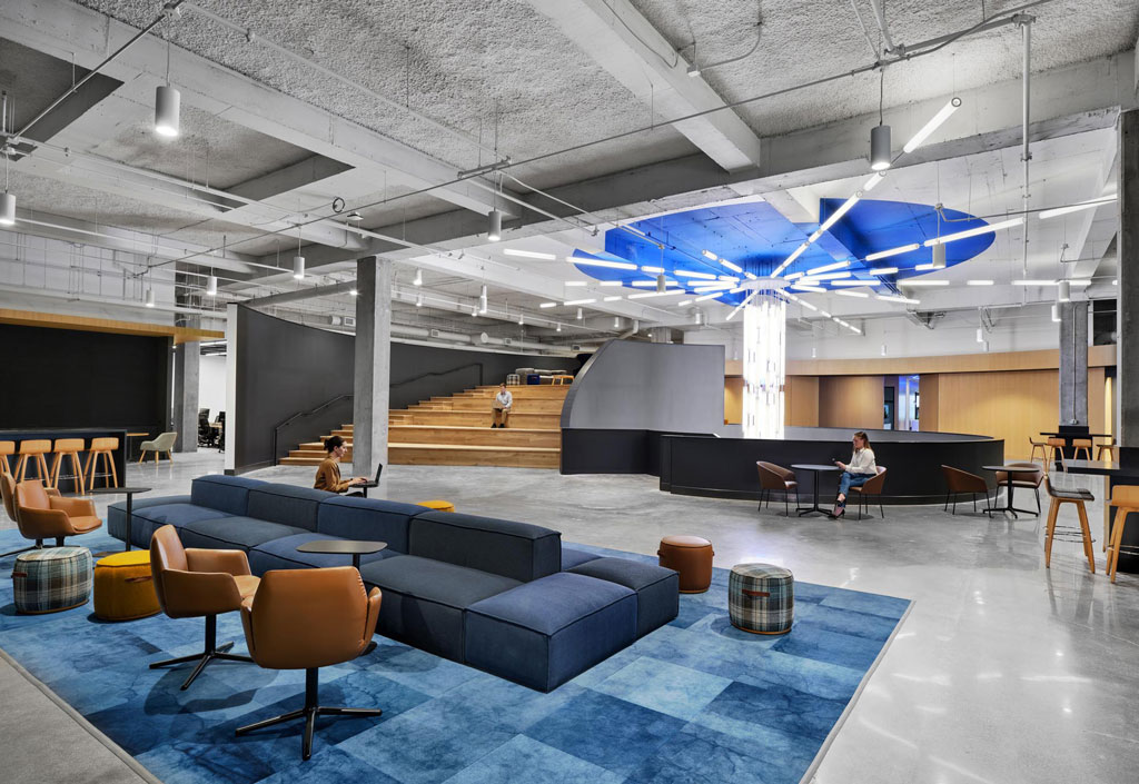 Office setting with a blue rug and seating and a ceiling feature light