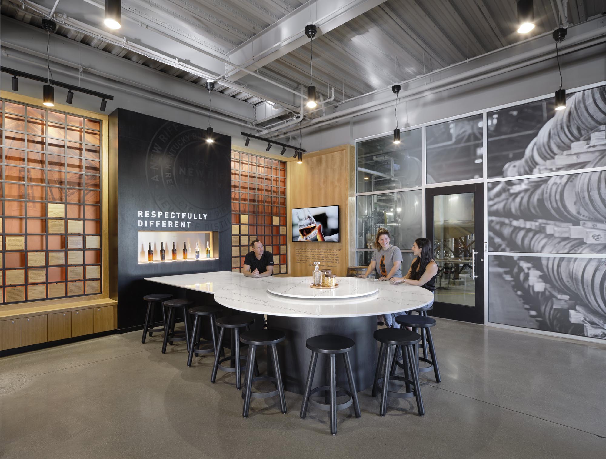 Visitors sit at the circular counter for bourbon tasting with branded graphics on surrounding walls.